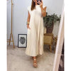 A woman wearing a cream pleated midi dress with a round neck standing in a bright room.
