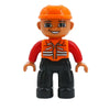 Una minifigura naranja con casco y camisa roja al lado de bloques negros.