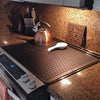A copper kettle and a silicone stove protector mat are displayed on a granite countertop.
