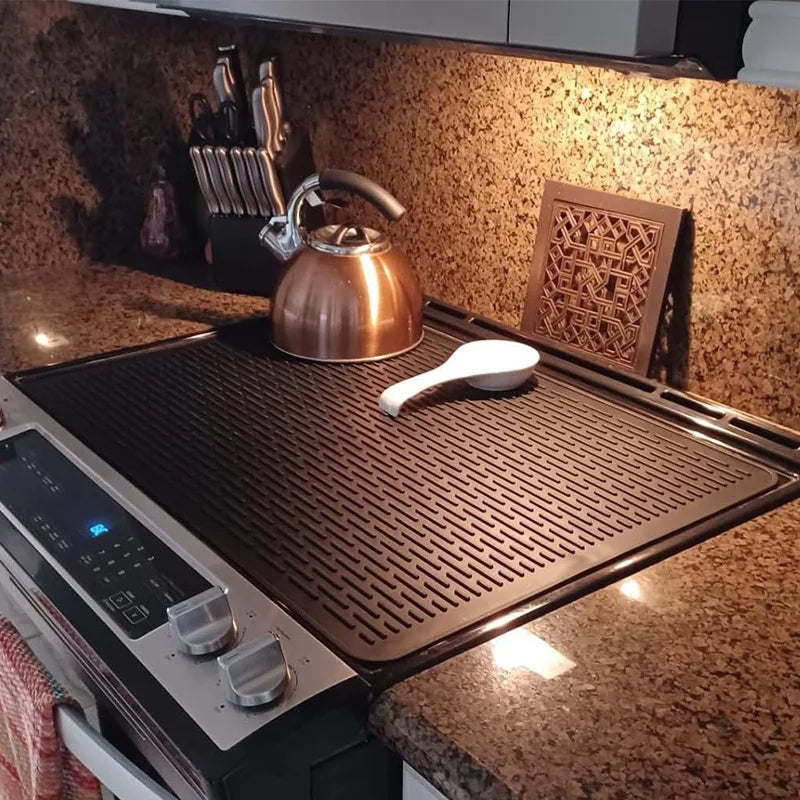 A copper kettle and a silicone stove protector mat are displayed on a granite countertop.