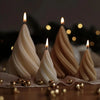 Three tapered candles glowing on a wooden surface with gold decorative balls.