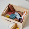 A wooden pretend play food cutting set in a light wood box filled with various shaped and colored food items.