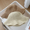 A beige crochet straw fisherman hat with a wide brim is displayed on a white tray.