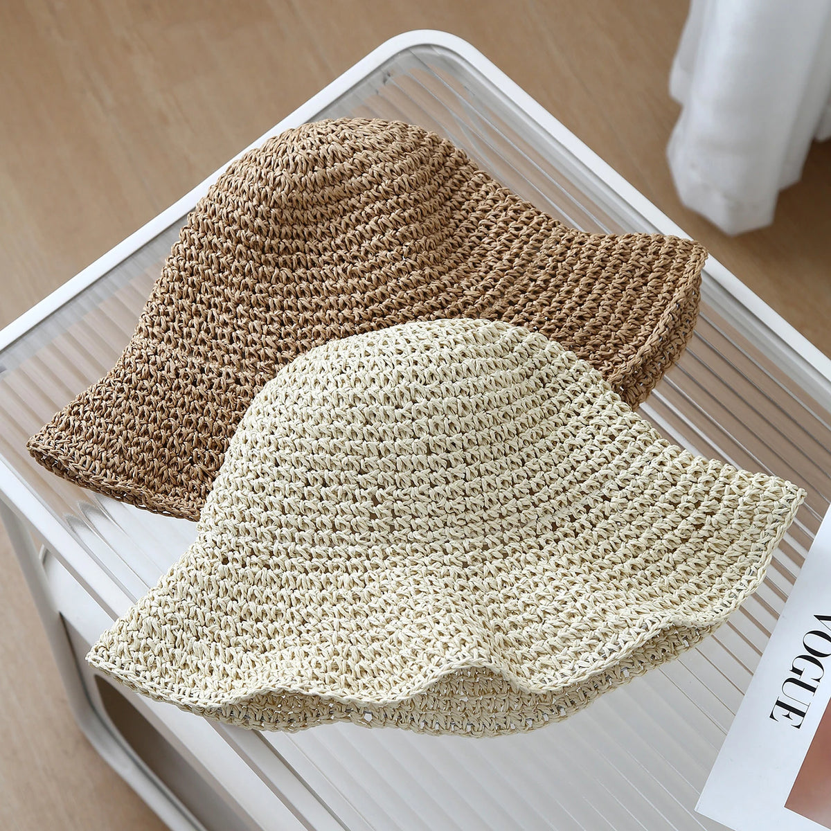 A beige crochet straw fisherman hat with a wide brim is displayed on a white tray.