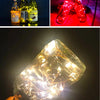 A close-up of a glass bottle filled with LED fairy lights, illuminating the interior and exterior.