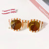 A pair of orange-tinted sunglasses with a striped frame resting on a white surface.