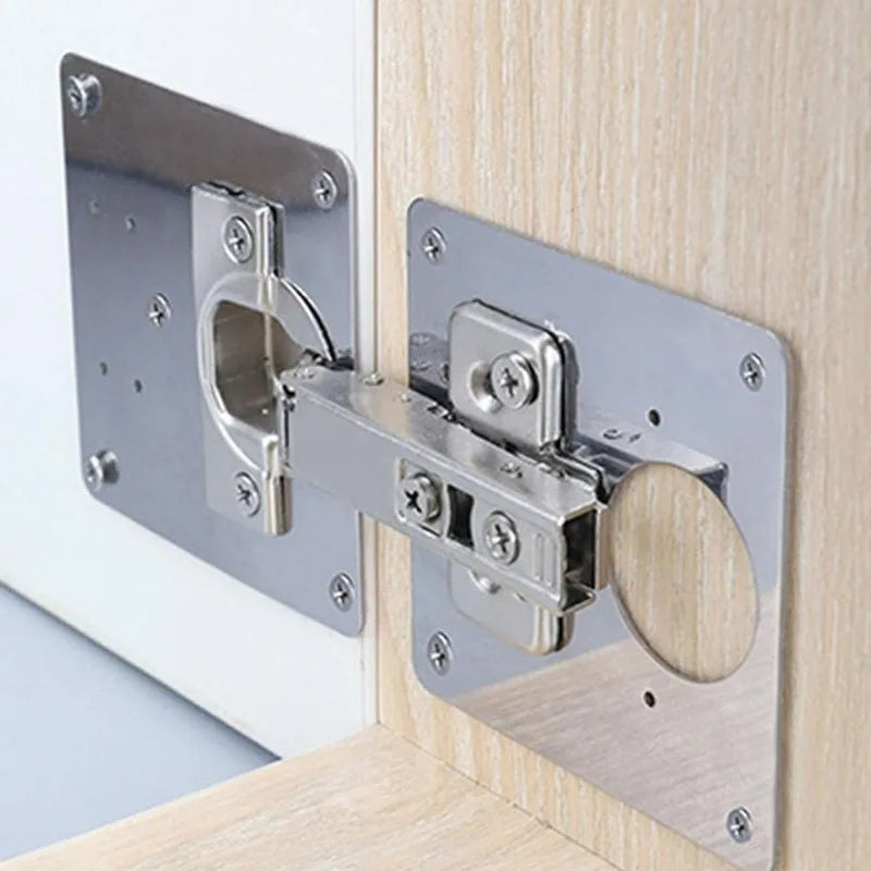 Stainless steel cabinet door hinge repair plate kit with screws mounted on a wooden cabinet frame.