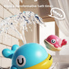A blue and yellow musical light-up whale bath toy spraying water in a bathtub.