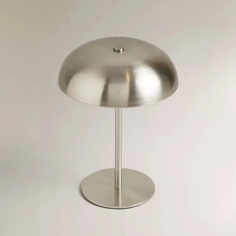 A modern, silver-toned portable touch table lamp with a dome shade and a cylindrical stand.