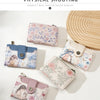 A display of various floral print women's wallets and card holders in pastel pink, blue, and cream colors.