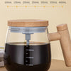 A clear glass mug filled with dark liquid is shown with a wooden handle, demonstrating various volume markings.