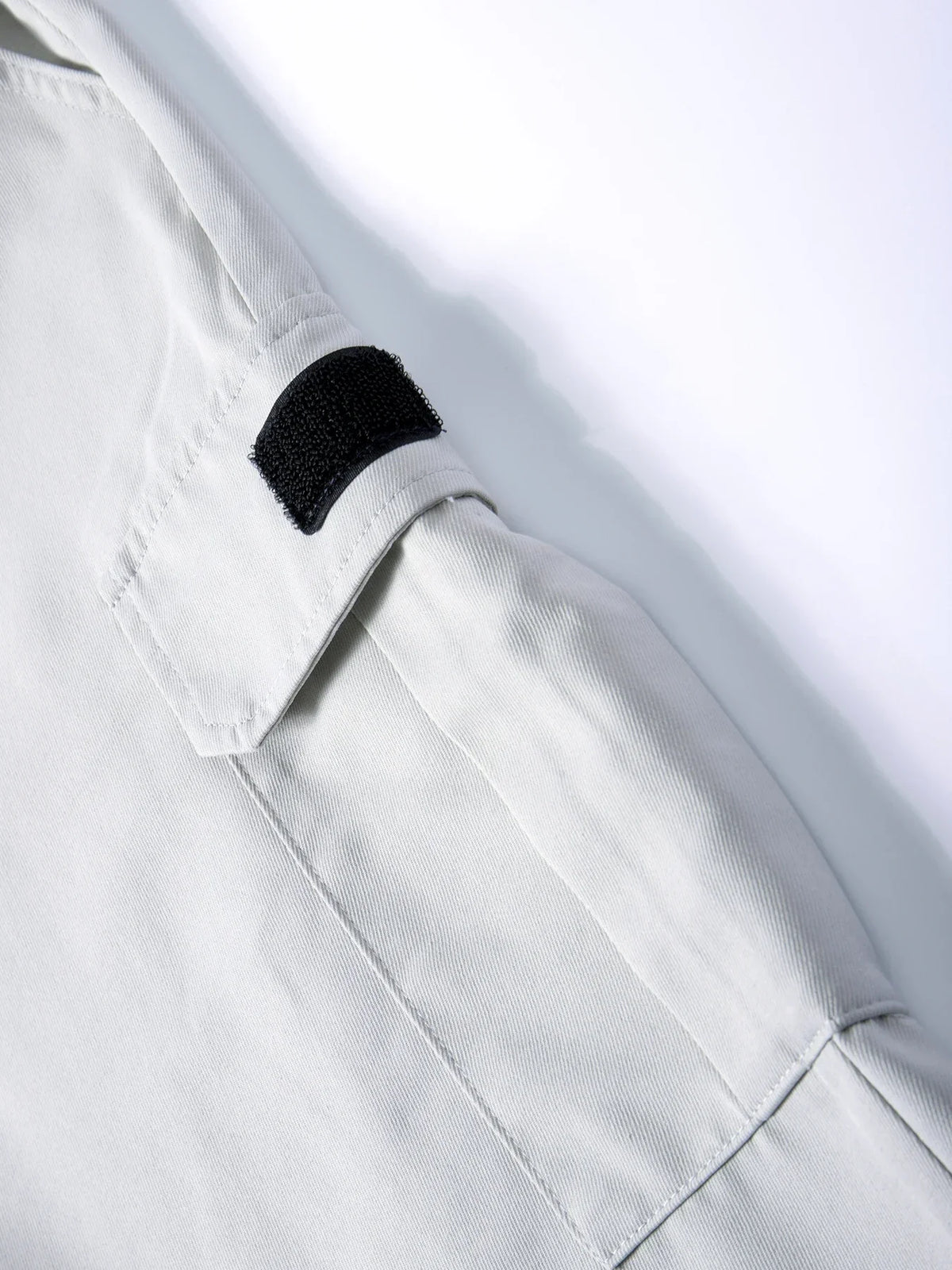 Close-up of a light gray men's cargo jogger featuring a black patch detail on the sleeve.