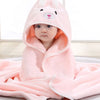 A baby wearing a pink hooded towel shaped like a bunny, lying down.
