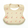 A beige waterproof silicone baby bib with a catch pocket featuring a pattern of small red and green leaves.