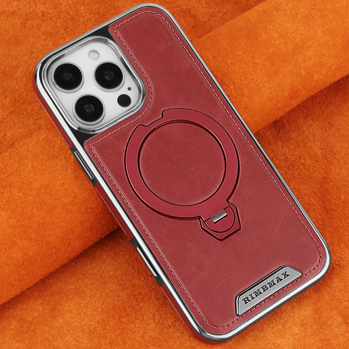 A maroon leather case with a magnetic stand design for an iPhone is shown resting on an orange fabric.