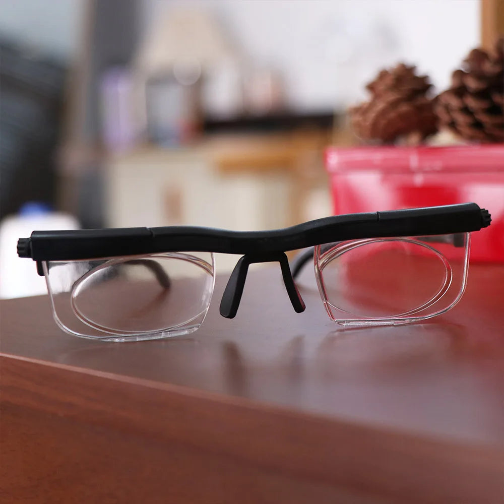 A pair of black frame reading glasses with clear lenses resting on a wooden surface.