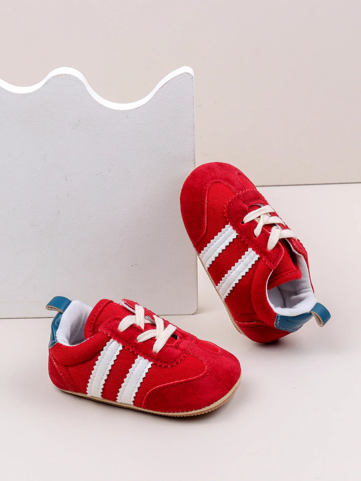 A pair of red and white Adidas style baby first walker shoes with anti-slip sole resting on a white background.