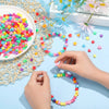 Hands are assembling a colorful beaded crown and scattered beads on a light blue surface.