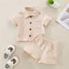 A beige linen shirt and matching shorts set for a toddler, laid out on a light surface.