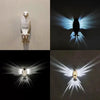 Wandlampe mit einer weißen Eulenskulptur und ausstrahlenden Lichtstrahlen.