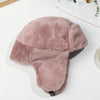 A soft, dusty rose colored Russian Ushanka trapper hat with a thick fur lining, shown on a white surface.