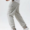 A man wearing light gray cargo joggers and a white shirt, showing the fit of the adjustable waist pants.