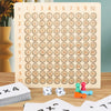 A wooden multiplication board game with numbered tiles laid out on a wooden surface next to playing cards.