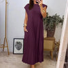 A woman wearing a long, purple pleated midi dress with a round neckline and gold bracelet.