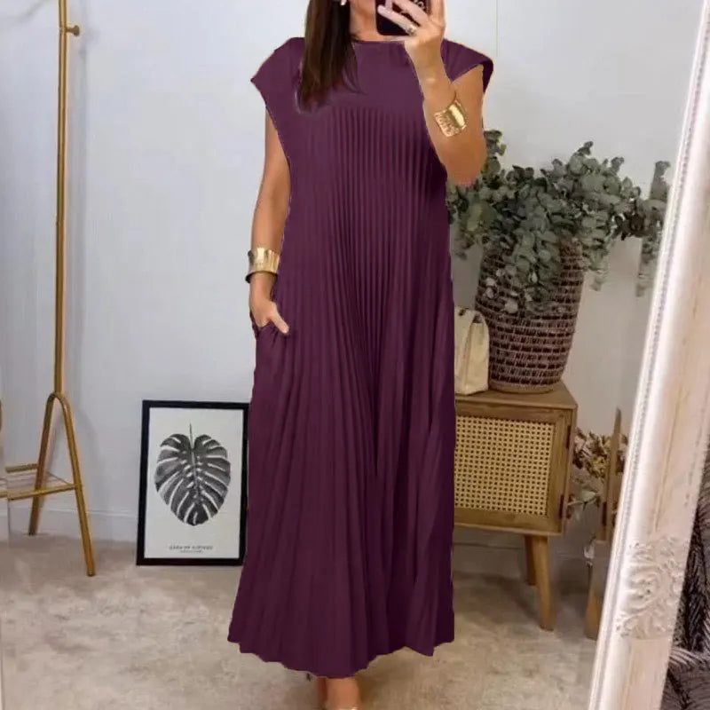 A woman wearing a long, purple pleated midi dress with a round neckline and gold bracelet.