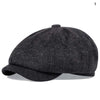 A dark gray vintage newsboy cap with a folded brim shown from the side.