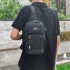 A man wearing a black t-shirt is carrying a black versatile crossbody backpack.