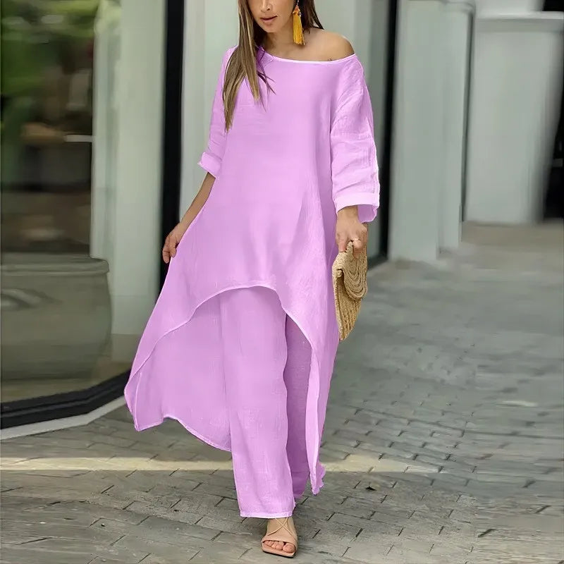 Kvinne modellerer et lilla lounge-sett i bomull og lin med off-shoulder-topp og vide bukser.