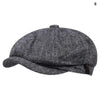 A dark gray vintage newsboy cap with a folded brim shown from above.
