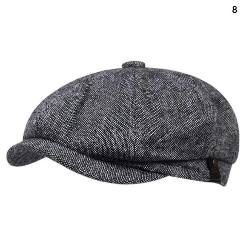 A dark gray vintage newsboy cap with a folded brim shown from above.