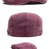 Vista cercana de una gorra newsboy de mezclilla lavada púrpura y polvorienta, con estilo retro de boina.