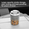 A clear glass car ashtray with a silver rotatable flip lid and a ceramic charcoal liner sitting on a white surface.