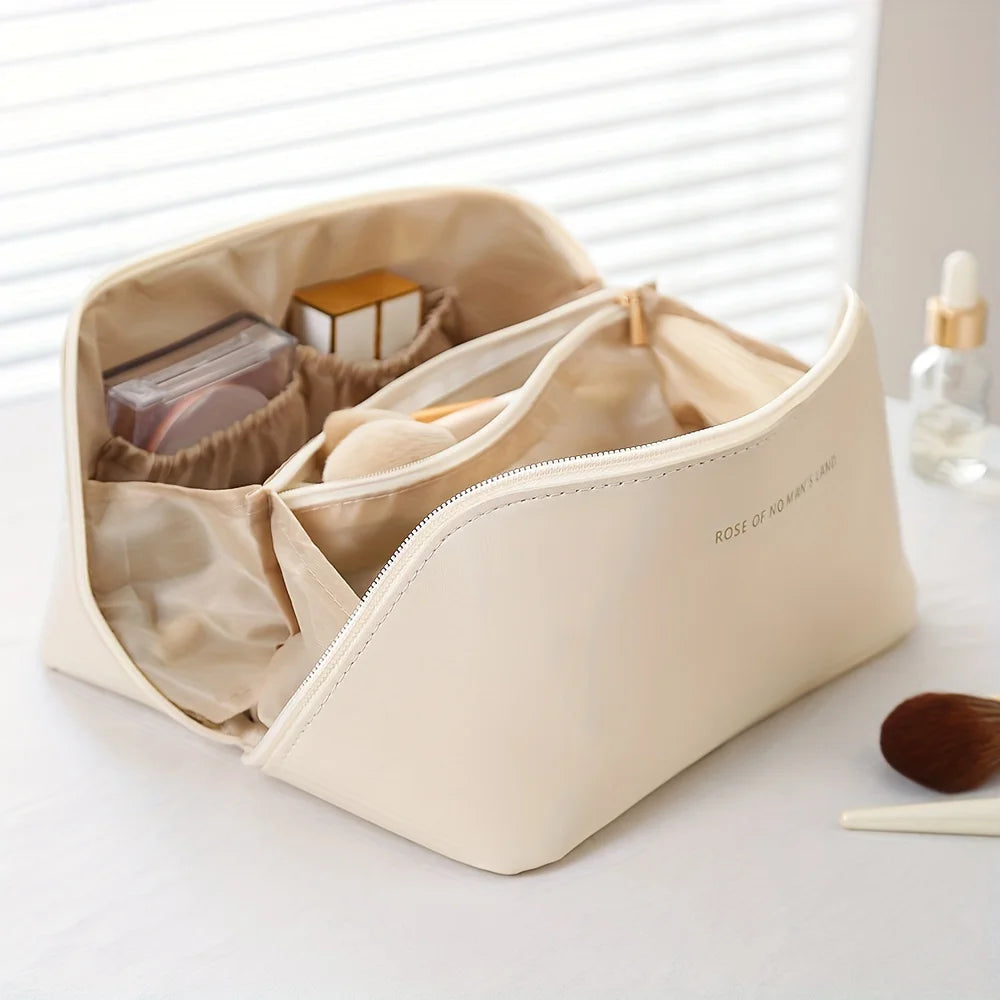 Beige rejsetaske til makeup i PU-læder med lynlås og trædetalje på hvid overflade.