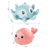 A light blue musical whale bath toy with large eyes and flippers is shown next to a pink version.