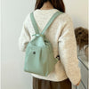 A woman wearing a cream-colored sweater carries a mint green lightweight Oxford cloth mini backpack.