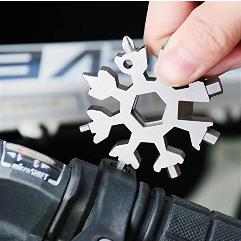 A hand is holding a silver multi-tool with various tips, being used on a black tool handle.