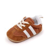 A pair of brown suede baby first walker shoes with white stripes and a white sole.