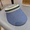 A woven straw sun hat with a wide brim and a striped band resting on a gray surface.