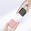 A hand is holding a pink silicone charger protector and cable organizer, with a black cable emerging from it.
