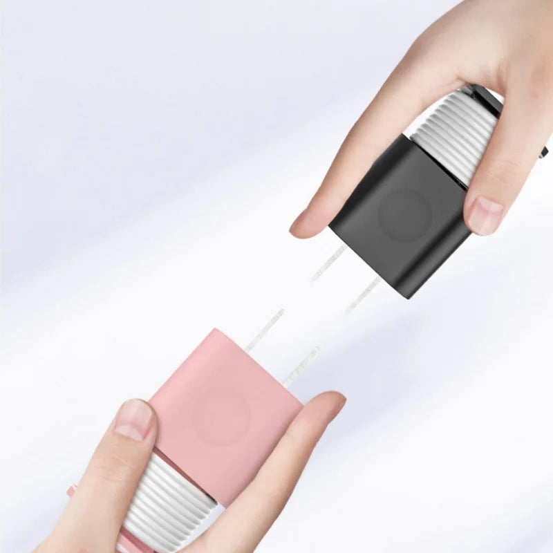 A hand is holding a pink silicone charger protector and cable organizer, with a black cable emerging from it.