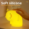 Un patito de silicona amarillo como luz nocturna sostenido en una mano, iluminando una superficie.