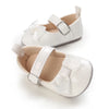 A pair of white soft non-slip baby first walker shoes with decorative bows.