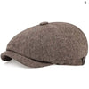 A close-up view of a brown tweed newsboy cap with a folded brim.