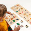 A child is interacting with a wooden Montessori fruit and animal matching puzzle set featuring various animals and fruits.