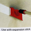 A red paint edger brush is shown against a light-colored wall, positioned next to an expansion stick.