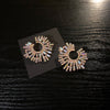 Pendientes de flor de cristal sobredimensionados sobre una superficie oscura.